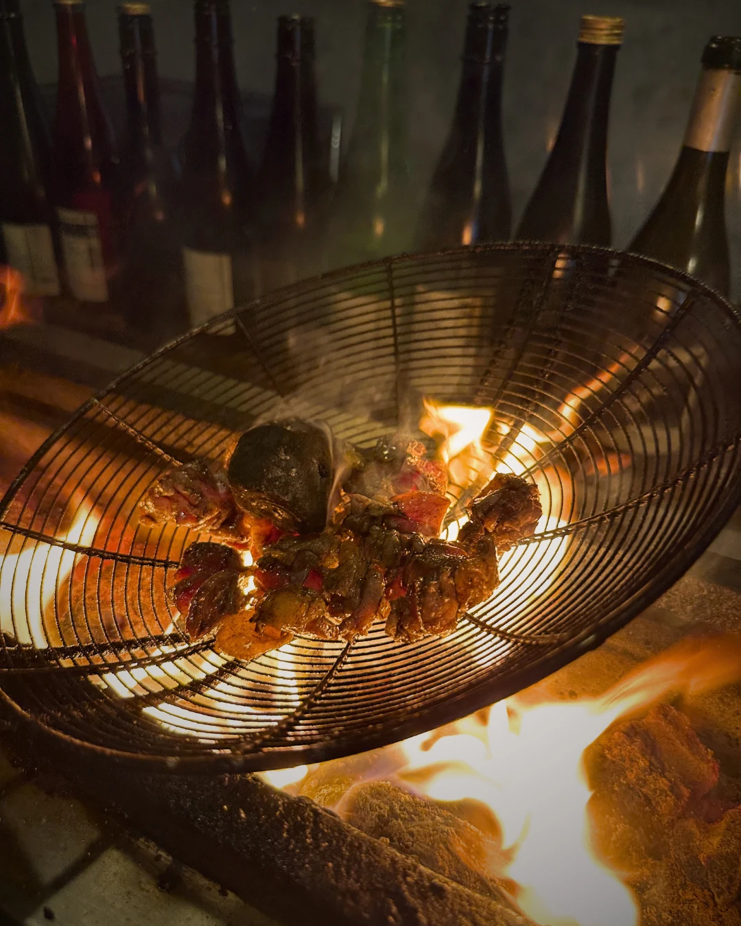 Binchotan charcoal glowing under hand-skewered yakitori, with sake bottles in the background