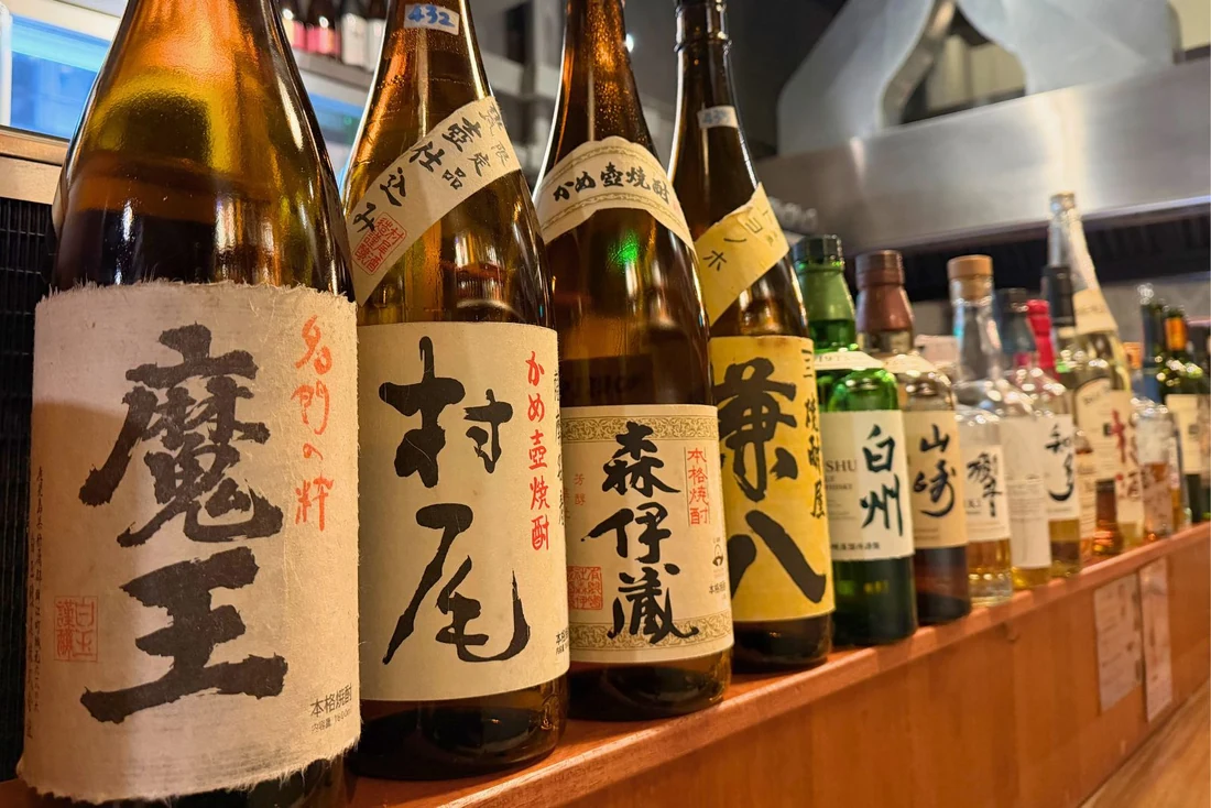 Shochu and spirits lined up on the counter at Sumibi Hirashima, Thonglor, Bangkok